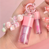 Two-piece Set Of Color-changing Lip Oils And A Bow-shaped Pearl Bracelet Charm.