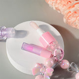 Two-piece Set Of Color-changing Lip Oils And A Bow-shaped Pearl Bracelet Charm.