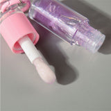 Two-piece Set Of Color-changing Lip Oils And A Bow-shaped Pearl Bracelet Charm.