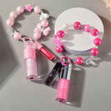 Two-piece Set Of Color-changing Lip Oils And A Bow-shaped Pearl Bracelet Charm.